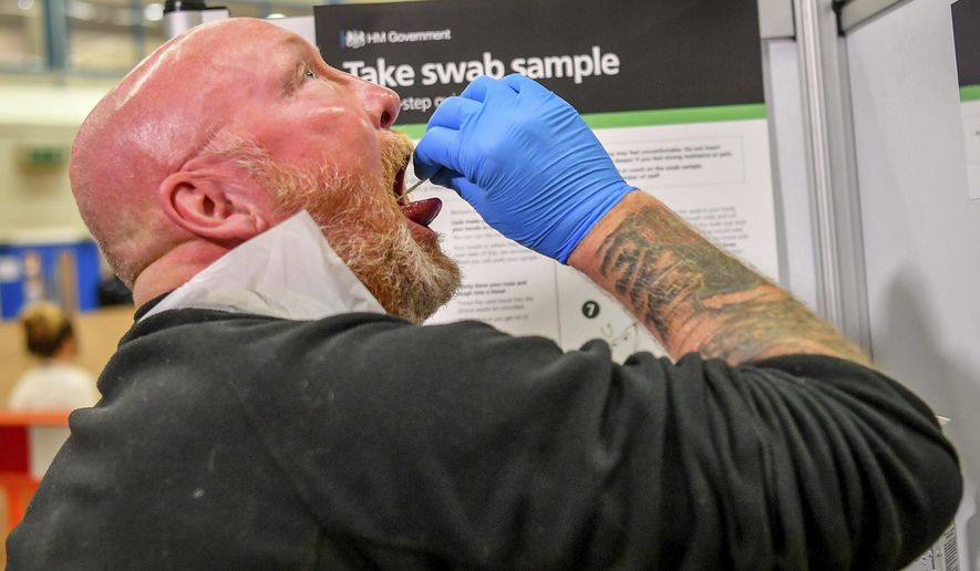 A testing staff member completes a lateral flow test swab, mandatory before opening to the public, at Rhydycar leisure centre in Merthyr Tydfil, Wales, Saturday, Nov. 21, 2020. where mass coronavirus testing begins following a two-week &amp;quot;firebreak&amp;quot; lockdown. (Ben Birchall/PA via AP)