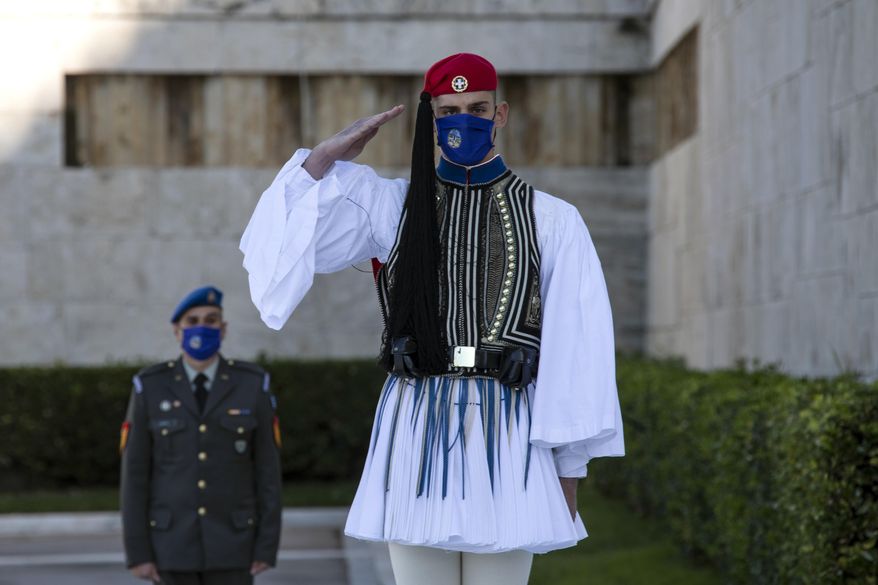 A Greek Presidential Guard, wearing a protective mask against the spread of coronavirus, salutes during a wreath laying ceremony, in Athens, Saturday, Nov. 21, 2020. The government imposed a second lockdown nationwide on Nov. 7, expanding regional restrictions, following a dramatic surge in COVID-19 cases. (AP Photo/Yorgos Karahalis)