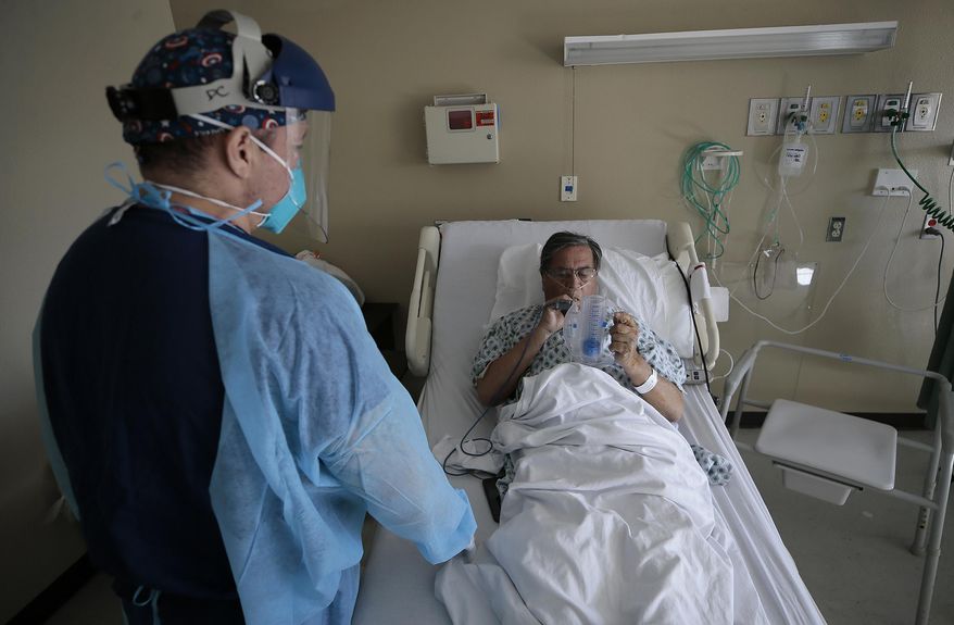 Registered Nurse Daniel Corral works with a COVID-19 patient at the El Paso Long Term Acute Care Hospital, Friday, Nov. 6, 2020, in El Paso, Texas. The relentless war against a deadly, invisible enemy was out of sight to all but those working its front lines. (Mark Lambie/The El Paso Times via AP)