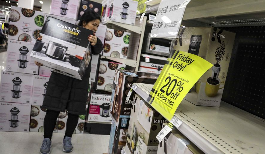 A shopper carries a crockpot during Target&#39;s Black Friday sale, in the Borough of New York. The National Retail Federation, the nation’s largest retail group,  expects that holiday sales could actually exceed growth seen in prior seasons despite the uncertainty surrounding the pandemic. (AP Photo/Bebeto Matthews, File)