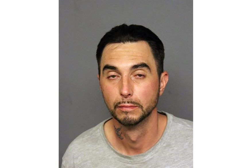 This undated booking photo provided by the Denver Police Department shows Derick Smialek who was being held on suspicion of reckless endangerment and arson. Denver police say Smialek was arrested on Sunday, Nov. 22, 2020, after firing a fire a flare gun into his car outside a police station. Police say the contents of the car were soaked with gasoline but nothing ignited. (Denver Police Department via AP)