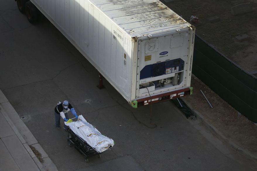 Medical workers use the mobile morgues near the El Paso Medical Examiner Monday, Nov. 9, 2020, as coronavirus cases spike in El Paso, Texas. County Judge Ricardo Samaniego said the county has requested four more trailers in addition to the six mobile morgues. (Briana Sanchez/The El Paso Times via AP)