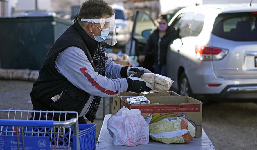 Food is loaded onto tables for those in need outside of the Catholic Community Services of Utah Friday, Nov. 20, 2020, in Ogden, Utah. As coronavirus concerns continue, the need for assistance has increased. (AP Photo/Rick Bowmer)