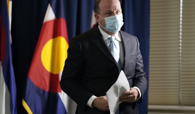 In this file photo, Colorado Governor Jared Polis wears a face mask as he leaves after a news conference about the state's response to the rapid increase in COVID-19 cases Tuesday, Nov. 24, 2020, in Denver. Mr. Polis has tested positive for COVID-19, he said in a statement released Nov. 28, 2020. (AP Photo/David Zalubowski)  **FILE**