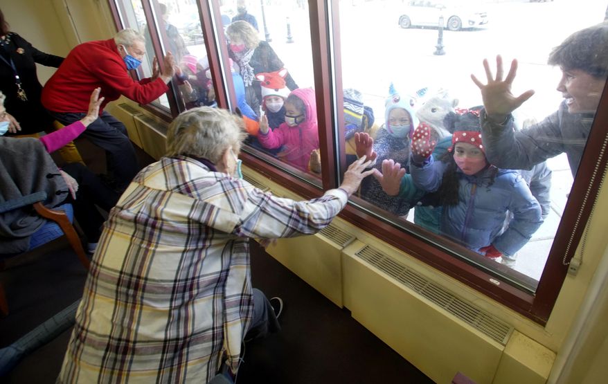 The pre-kindergarten group from the Boys and Girls Club visit through the window with members of the supportive daycare program at the Froio Senior Center in Pittsfield, Mass., Tuesday, Nov. 24, 2020. (Ben Garver/The Berkshire Eagle via AP)