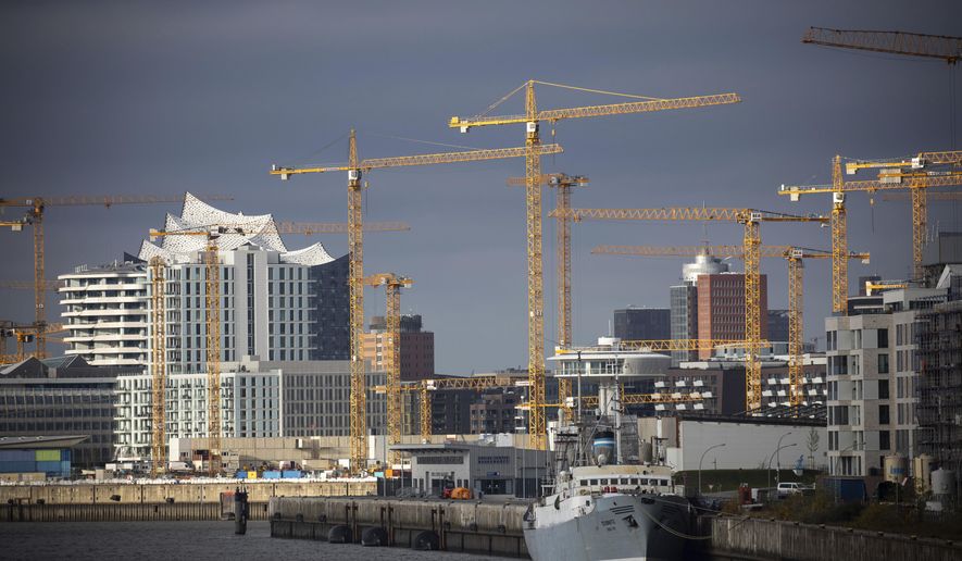 Construction cranes are located at various construction sites at Bakenhafen and Ueberseequartier in Hafencity in Hamburg, Germany, Monday, Nov. 16, 2020. In the background you can see the striking roof silhouette of the Elbe Philharmonic Hall. (Christian Charisius/dpa via AP)