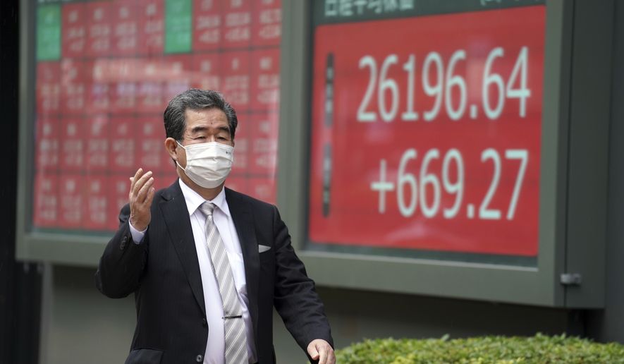 A man wearing a protective face mask to help curb the spread of the coronavirus walks past an electronic stock board showing Japan&#x27;s Nikkei 225 index at a securities firm in Tokyo Tuesday, Nov. 24, 2020.　Asian shares were mostly higher Tuesday, encouraged by news on the development of coronavirus vaccines and more assurance for a transition of power in the U.S. to President-elect Joe Biden. (AP Photo/Eugene Hoshiko)