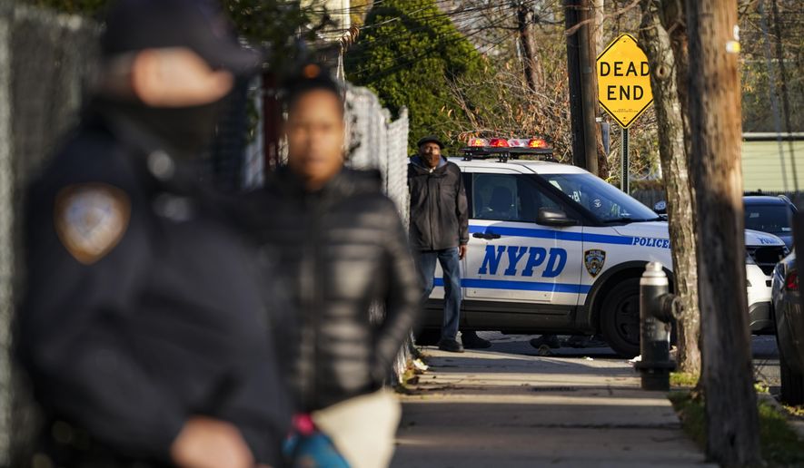 Police maintain a perimeter outside a crime scene, Tuesday, Nov. 24, 2020, in the Queens borough of New York. Two New York City police officers were wounded Tuesday afternoon by a man who opened fire as they arrived for a wellness check at a home with a history of domestic violence, a law enforcement official said. (AP Photo/John Minchillo)