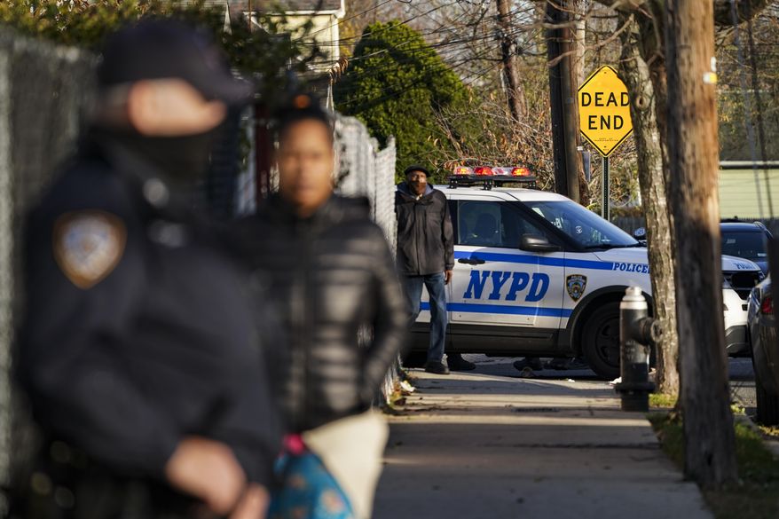 Police maintain a perimeter outside a crime scene, Tuesday, Nov. 24, 2020, in the Queens borough of New York. Two New York City police officers were wounded Tuesday afternoon by a man who opened fire as they arrived for a wellness check at a home with a history of domestic violence, a law enforcement official said. (AP Photo/John Minchillo)