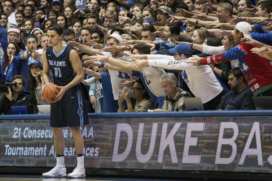 FILE- In this Dec. 3, 2016, file photo, Maine's Ilija Stojiljkovic (11) looks to in-bound the ball as the Cameron Crazies shout from behind during an NCAA college basketball game against Duke in Durham, N.C. As the season begins in earnest this week, with a full slate of Division I games Wednesday, fans will notice the absence of traditions such as the Silent Night game across the college basketball landscape. The population of Krzyzewskiville at Duke will be zero, the Oakland Zoo at Pittsburgh a bit more tame. The Orange Crush at Illinois will be less intimidating and the ghost-like sound of “Rock Chalk Jayhawk” at Kansas will be merely the echoes from thousands of previous wins.   (AP Photo/Ben McKeown, File)