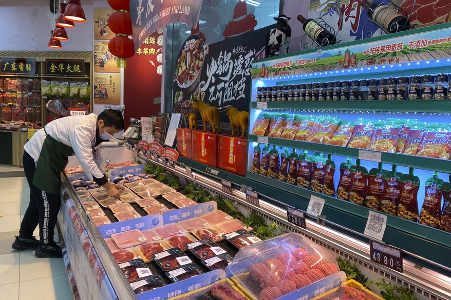 A worker wearing a mask handles meat products including beef from New Zealand packaged with a QR-code linked to its COVID test results at a supermarket in Beijing, Tuesday, Nov. 24, 2020. China has stirred controversy with claims it has detected the coronavirus on packages of imported frozen food. (AP Photo/Ng Han Guan)