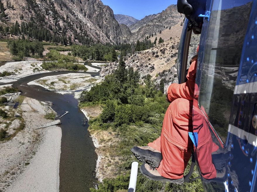 This Sept. 9, 2020 photo provided by the Idaho Department of Fish and Game shows Idaho Department of Fish and Game fisheries biologist Eli Felts looking down at Loon Creek to count chinook salmon spawning beds in the Frank Church River of No Return Wilderness, Idaho. (Conor McLure/Idaho Department of Fish and Game via AP)