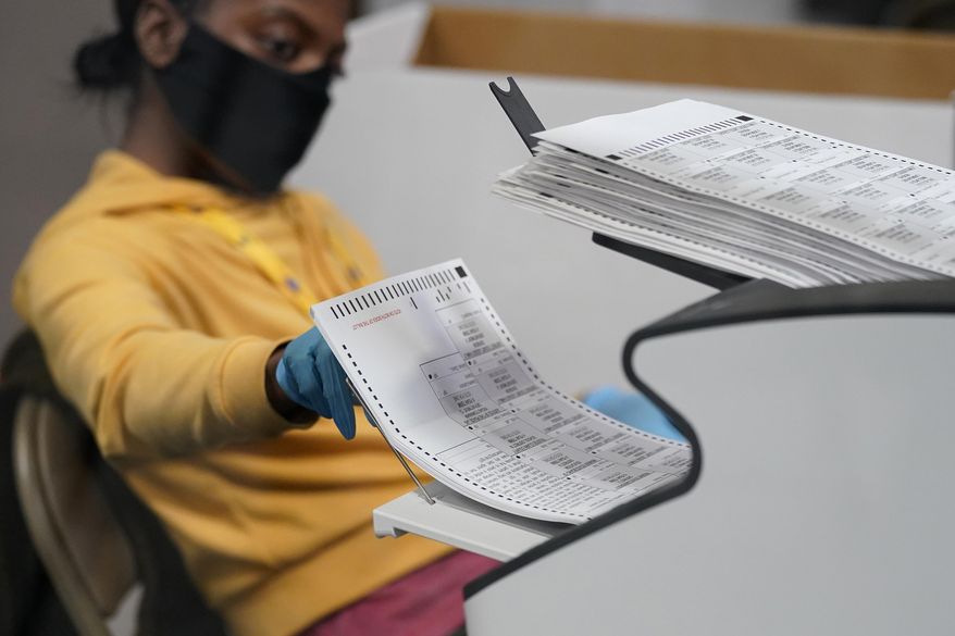 A county election worker scans mail-in ballots at a tabulating area at the Clark County Election Department in Las Vegas, Nov. 5, 2020. (AP Photo/John Locher) ** FILE **