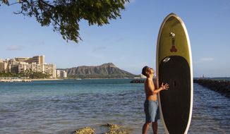 In this photo provided by Yoko Liriano, Bryant de Venecia poses for a photo with his paddleboard in Honolulu, Wednesday, Nov. 11, 2020. He started stand-up paddle-boarding when there were fewer tourists coming to Hawaii during the pandemic. He&#39;s among the Hawaii residents feeling ambivalence toward tourists returning now that the state is allowing incoming travelers to bypass a 14-day quarantine with a negative COVID-19 test. (Yoko Liriano via AP)