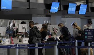 Travelers wearing masks check in at United desks at San Francisco International Airport during the coronavirus outbreak in San Francisco, Tuesday, Nov. 24, 2020. (AP Photo/Jeff Chiu)