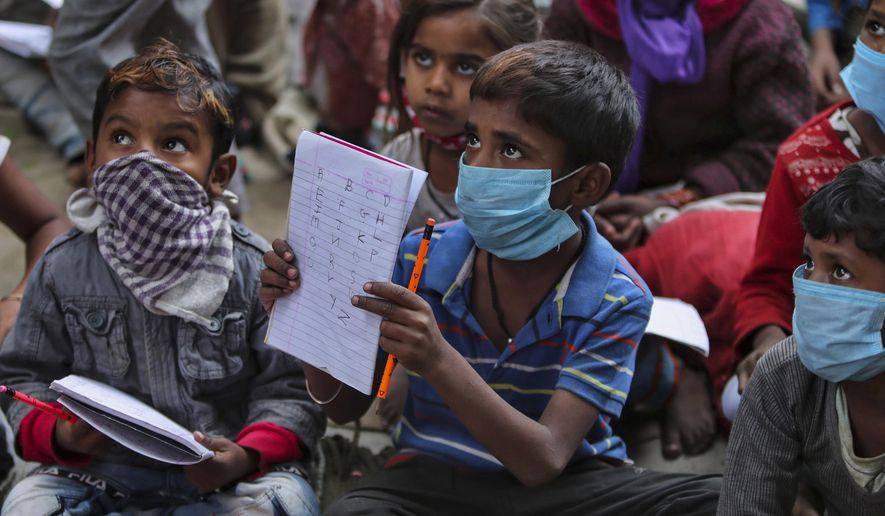 Underprivileged children wearing face masks as a precaution against the coronavirus attend a class at the Sangharsh Vidya Kendra school at a slum area on the outskirts of Jammu, India, Wednesday, Nov.25, 2020. The school provides free education to underprivileged children two days a week. (AP Photo/Channi Anand)