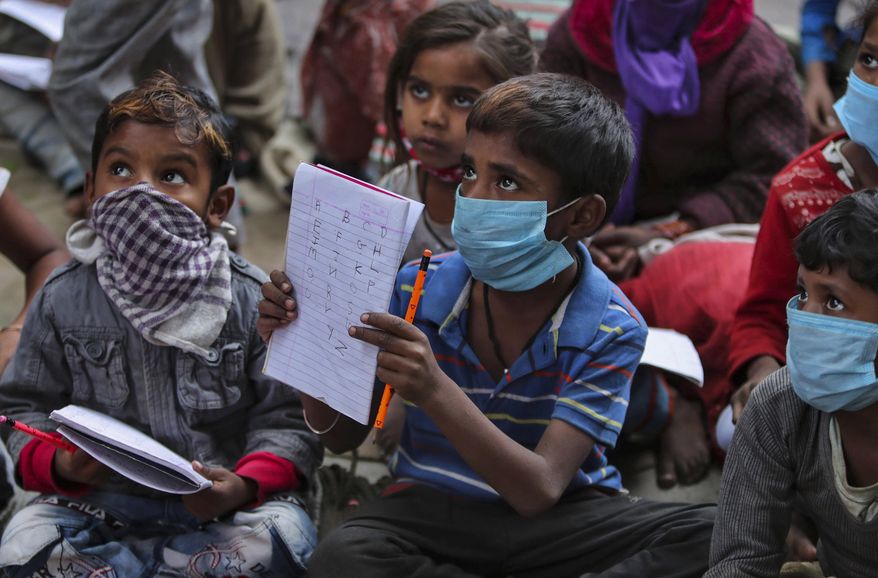 Underprivileged children wearing face masks as a precaution against the coronavirus attend a class at the Sangharsh Vidya Kendra school at a slum area on the outskirts of Jammu, India, Wednesday, Nov.25, 2020. The school provides free education to underprivileged children two days a week. (AP Photo/Channi Anand)