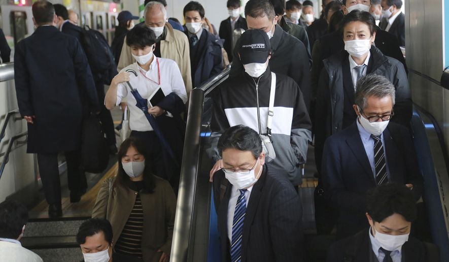 People wearing face masks to protect against the spread of the coronavirus arrive at the train station in Tokyo, Wednesday, Nov. 25, 2020. (AP Photo/Koji Sasahara)
