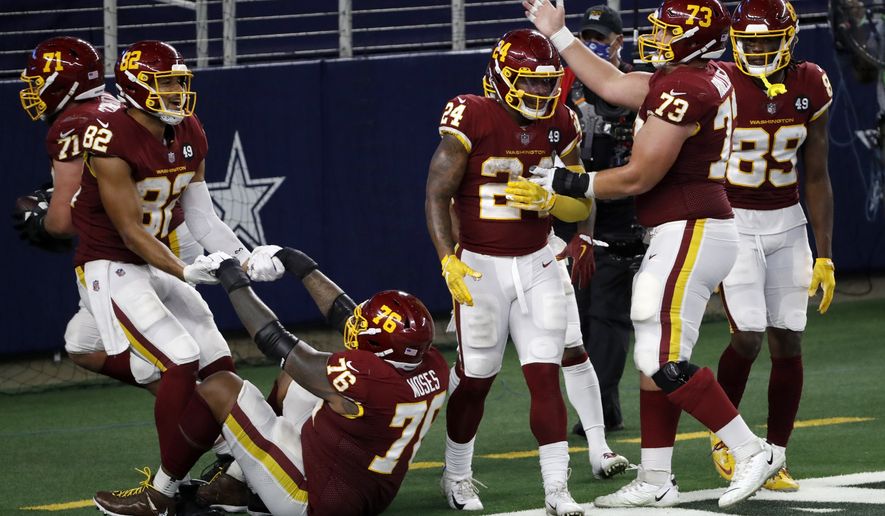 Washington Football Team&#39;s Antonio Gibson (24) is congratulated by Chase Roullier (73) and others after his touchdown run in the second half of an NFL football game against the Dallas Cowboys in Arlington, Texas, Thursday, Nov. 26, 2020. (AP Photo/Roger Steinman)