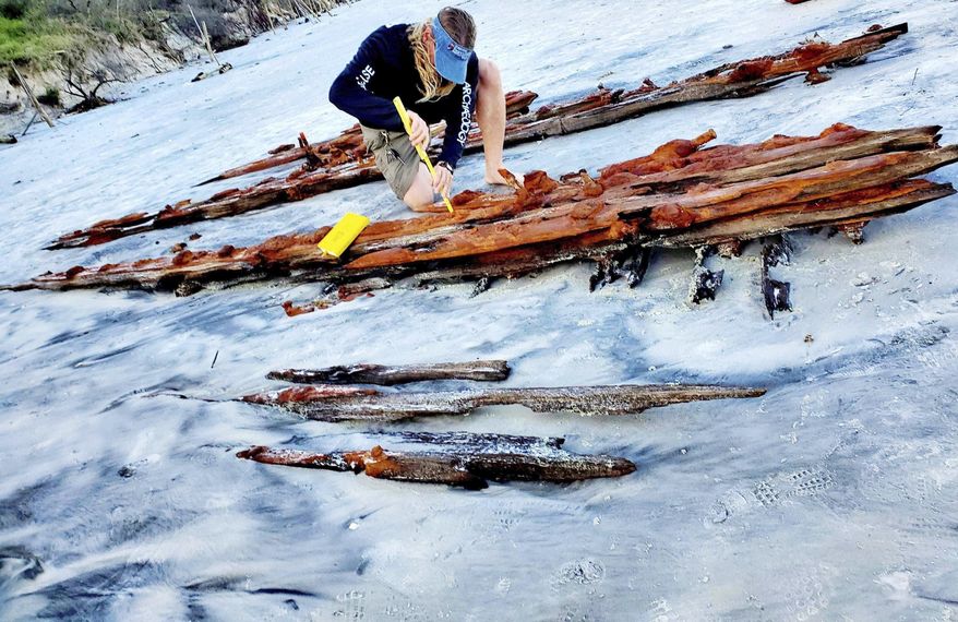 Chuck Meide, director of the Lighthouse Archeological Maritime Program in St. Augustine, takes measurements of the shipwreck that surfaced near Crescent Beach Saturday. (Colleen Michele Jones/The St. Augustine Record via AP)