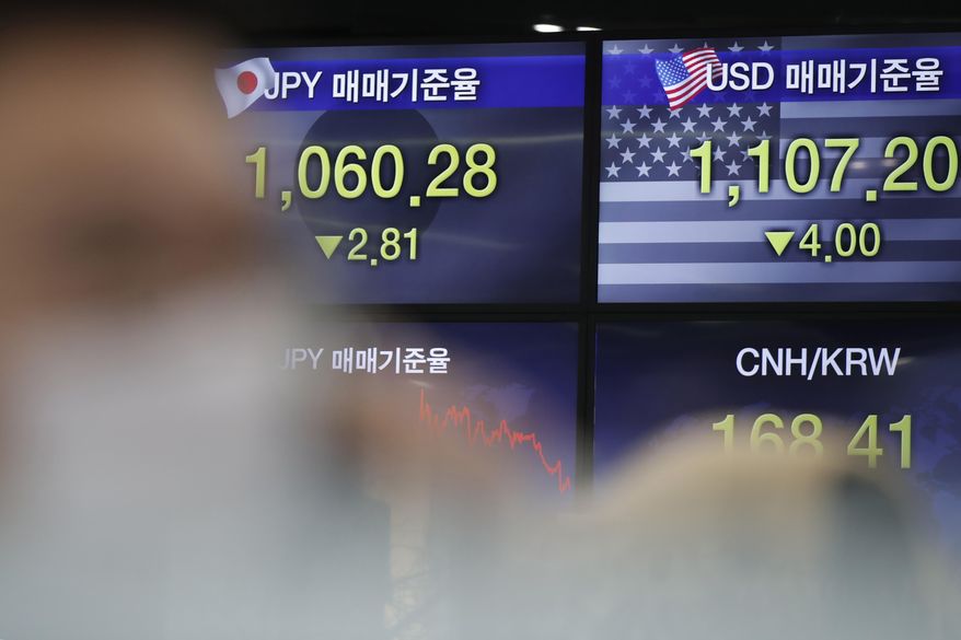 A currency trader talks on the phone near the screens showing the foreign exchange rates at the foreign exchange dealing room in Seoul, South Korea, Thursday, Nov. 26, 2020. Asian shares were mixed Thursday, after Wall Street took a pause from the optimism underlined in a record-setting climb earlier in the week. (AP Photo/Lee Jin-man)