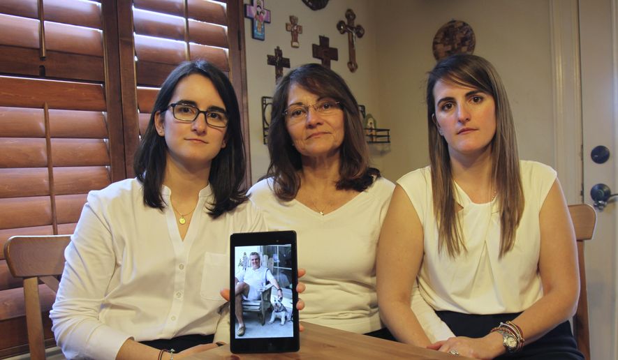 FILE - In this Feb. 15, 2019 file photo, Dennysse Vadell sits between her daughters Veronica, right, and Cristina holding a digital photograph of father and husband Tomeu who is currently jailed in Venezuela, in Katy, Texas. Tomeu Vadell, who is one of six U.S. oil executive jailed for three years in Venezuela, says in a letter from prison provided to The Associated Press on Tuesday, Nov. 24, 2020, that it’s especially painful to be separated during the Thanksgiving season from from his wife, three adult children and a newborn grandson he’s never held.  (AP Photo/John L Mone, File)