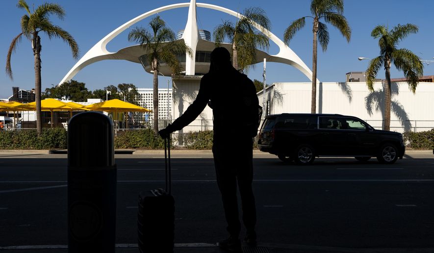 A travelers awaits for transportation at the Los Angeles International Airport in Los Angeles Wednesday, Nov. 25, 2020. Residents were urged to avoid nonessential travel during what is typically the busiest travel period of the year. Anyone entering California was advised to quarantine for two weeks. (AP Photo/Damian Dovarganes)