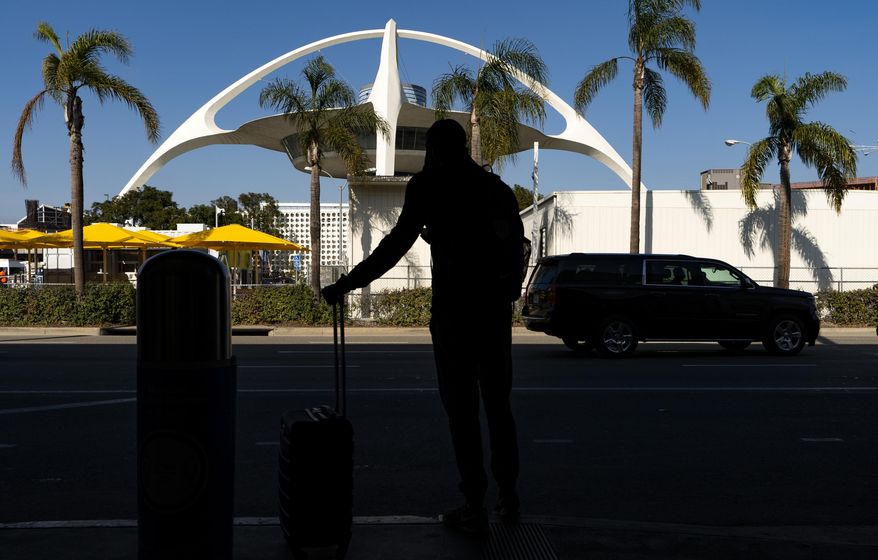 A travelers awaits for transportation at the Los Angeles International Airport in Los Angeles Wednesday, Nov. 25, 2020. Residents were urged to avoid nonessential travel during what is typically the busiest travel period of the year. Anyone entering California was advised to quarantine for two weeks. (AP Photo/Damian Dovarganes)