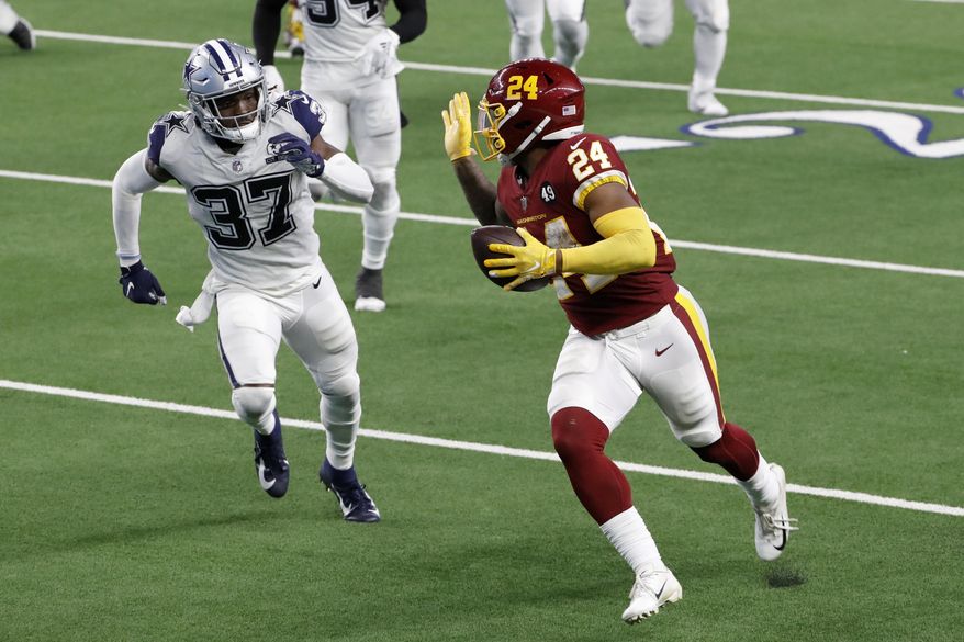 Washington Football Team running back Antonio Gibson (24) gestures with his hand as he gets past Dallas Cowboys safety Donovan Wilson (37) on his way to the end zone for a touchdown in the second half of an NFL football game in Arlington, Texas, Thursday, Nov. 26, 2020. (AP Photo/Roger Steinman)