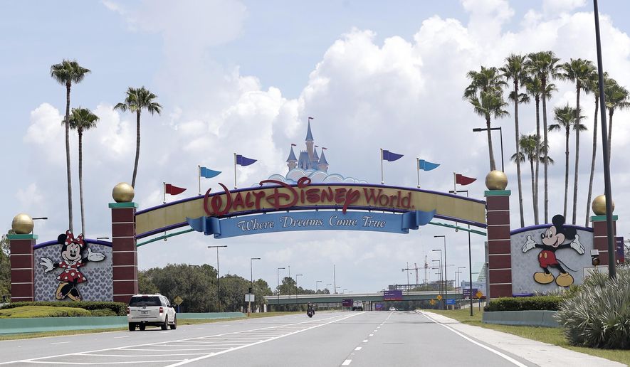 FILE - In this Thursday, July 2, 2020, file photo, cars drive under a sign greeting visitors near the entrance to Walt Disney World, in Lake Buena Vista, Fla.   The Walt Disney Co. is announcing plans to lay off 4,000 more workers in its theme parks division in California and Florida due to the COVID-19 pandemic&#x27;s effect on the industry. The company has been limiting attendance at its parks and changing protocols to allow for social distancing. (AP Photo/John Raoux, File)