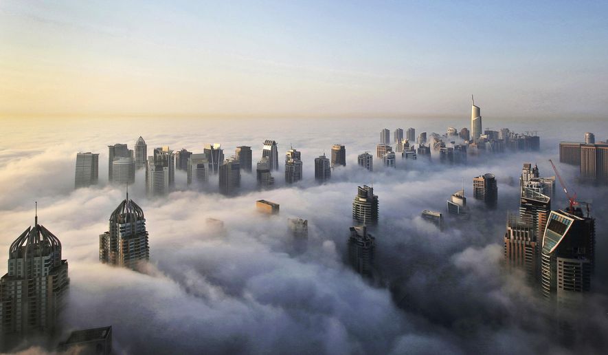 FILE - In this Monday, Oct. 5, 2015 file photo, a thick blanket of early morning fog partially shrouds the skyscrapers of the Marina and Jumeirah Lake Towers districts of Dubai, United Arab Emirates. Travel agencies in countries across the Middle East and Africa say the United Arab Emirates has temporarily halted issuing new visas to their citizens, a so-far unexplained ban on visitors amid both the coronavirus pandemic and as the UAE normalizes ties with Israel. (AP Photo/Kamran Jebreili, File)