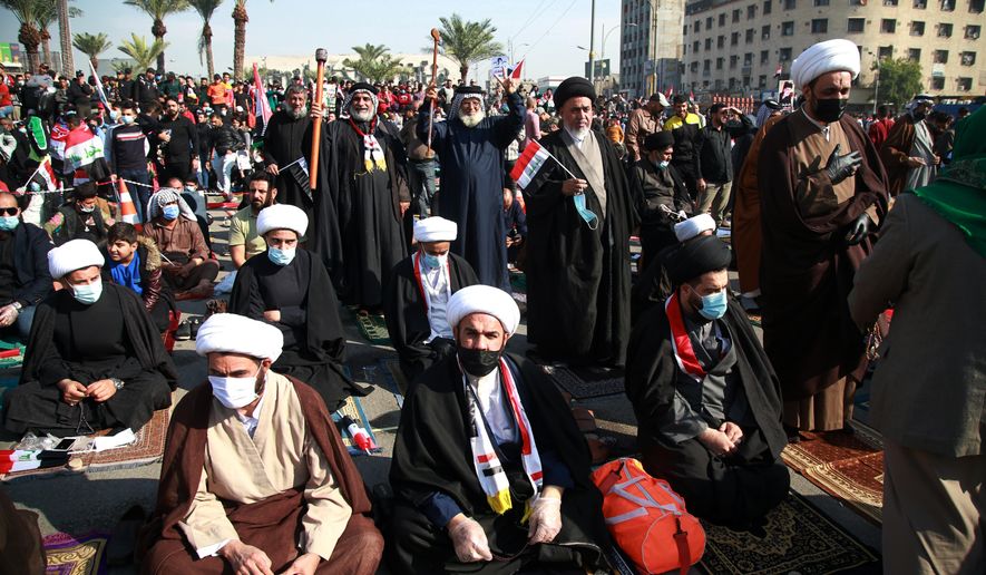 Followers of Shiite cleric Muqtada al-Sadr,gather in Tahrir Square, Baghdad, Iraq, Friday, Nov. 27, 2020. Thousands took to the streets in Baghdad on Friday in a show of support for a radical Iraqi cleric ahead of elections slated for next year, stirring fears of a spike in coronavirus cases. (AP Photo/Khalid Mohammed)