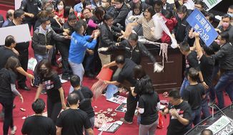 In this image made from video, lawmakers fight during a parliament session in Taipei, Taiwan, Friday, Nov. 27, 2020. Taiwan&#x27;s lawmakers got into a fist fight and threw pig guts at each other Friday over a soon-to-be enacted policy that would allow imports of U.S. pork and beef. A blue banner at right reads: “Protest against ractopamine pork, We want a referendum.” (FTV via AP)
