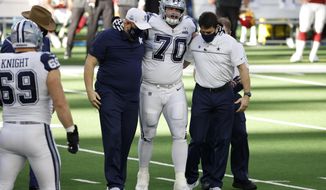 Dallas Cowboys guard Zack Martin (70) is assisted off the field by team medical staff after suffering an unknown injury in the first half of an NFL football game against the Washington Football Team in Arlington, Texas, Thursday, Nov. 26, 2020. (AP Photo/Ron Jenkins)