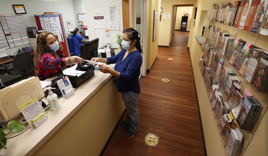 Eleanor Sanchez, manager of CrossOver Healthcare Ministry&#39;s Richmond clinic, helps Sara Eunice Cruz check out Tuesday, Oct. 27, 2020. (Alexa Welch Edlund/Richmond Times-Dispatch via AP)