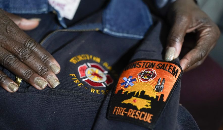 Timika Ingram holds a jacket she had when she was a firefighter on Thursday, Nov. 19, 2020, in Charlotte, N.C. A group of Black firefighters in a North Carolina city have filed a grievance over conditions they have endured for more than 30 years. (AP Photo/Chris Carlson)