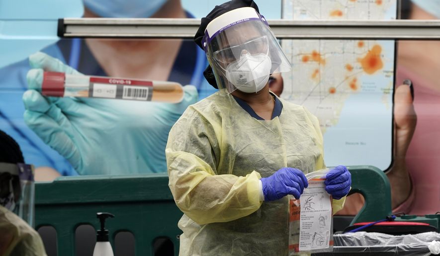 A health care employee works at a COVID-19 testing site at Crandon Park, Saturday, Nov. 28, 2020, in Miami. (AP Photo/Lynne Sladky)