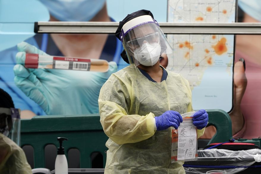 A health care employee works at a COVID-19 testing site at Crandon Park, Saturday, Nov. 28, 2020, in Miami. (AP Photo/Lynne Sladky)