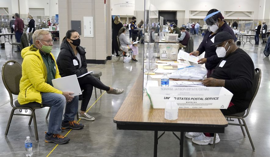 Election workers, right, verify ballots as recount observers, left, watch during a Milwaukee hand recount of presidential votes at the Wisconsin Center, Friday, Nov. 20, 2020, in Milwaukee. (AP Photo/Nam Y. Huh)