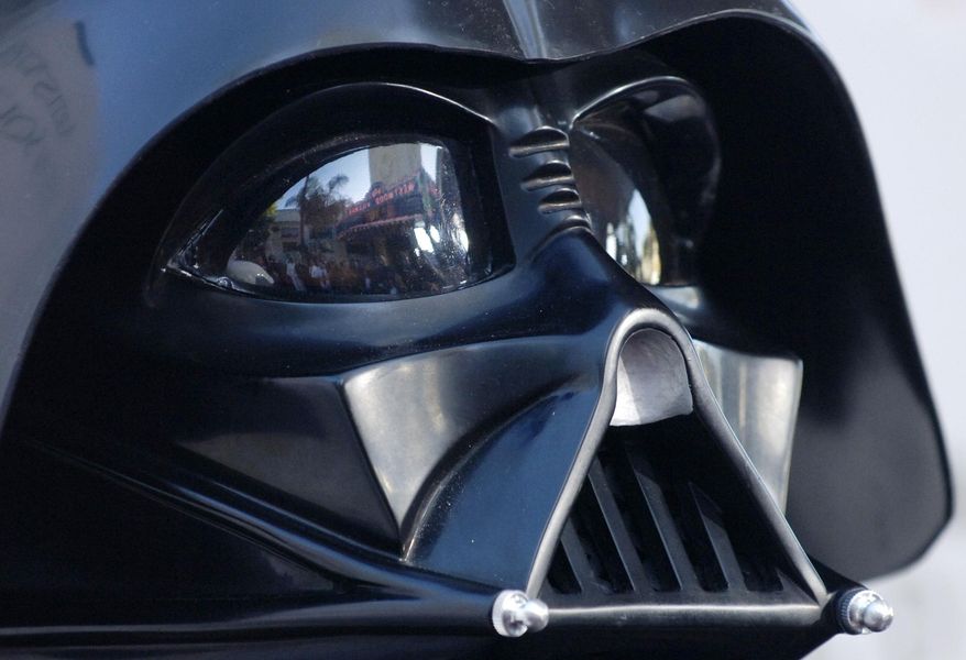 In this file photo dated Thursday, May 12, 2005, the Los Angeles, USA, premiere of the movie "Star Wars: Revenge of the Sith", is reflected in the mask eyeglasses of iconic baddie character Darth Vader. The British actor, Prowse who played Darth Vader in the original Star Wars trilogy, has died aged 85 on Saturday, according to an announcement by his agent Sunday Nov. 29, 2020. (AP Photo/Chris Pizzello, FILE)
