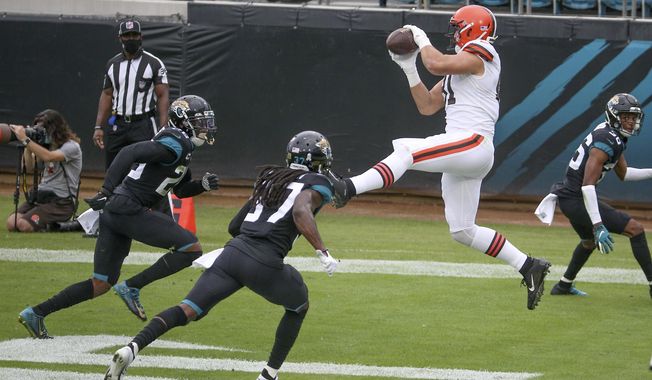 Cleveland Browns tight end Austin Hooper, right, catches a touchdown pass in front of Jacksonville Jaguars safety Jarrod Wilson, left, and cornerback Tre Herndon, center, during the first half of an NFL football game, Sunday, Nov. 29, 2020, in Jacksonville, Fla. (AP Photo/Stephen B. Morton)