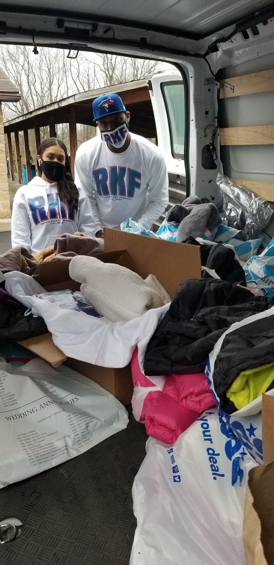 Indigo Martinez, left, and Rashod Kent select a coat from among the 150 given away on Saturday, Nov. 21, 2020 at Windmill Park in Fairmont, W.Va. Kent, now 40, and retired from athletic competition, returned to Windmill Park on Saturday, but this time as the face of the Rashod Kent Foundation, a nonprofit organization he formed this year in order to give back to a local community he said played a crucial role in his formative years. (Scott Gillespie/Times-West Virginian via AP)
