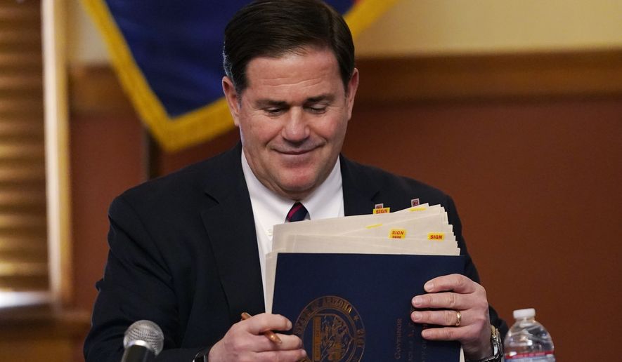 Arizona Gov. Doug Ducey organizes his signed election documents as part of the certification of the election results for federal, statewide, and legislative offices and statewide ballot measures at the official canvass at the Arizona Capitol, Monday, Nov. 30, 2020, in Phoenix. (AP Photo/Ross D. Franklin, Pool)