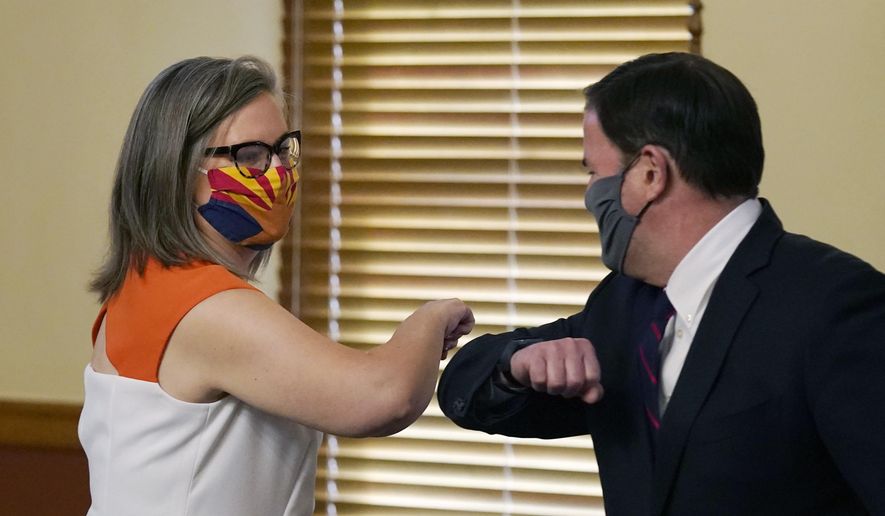 Arizona Secretary of State Katie Hobbs, left, and Arizona Gov. Doug Ducey bump elbows as they meet to certify the election results for federal, statewide, and legislative offices and statewide ballot measures at the official canvass at the Arizona Capitol Monday, Nov. 30, 2020, in Phoenix. (AP Photo/Ross D. Franklin, Pool)