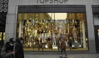 People wearing face masks to try to curb the spread of coronavirus walk past the temporarily closed Topshop flagship store on Oxford Street, during England&#39;s second coronavirus lockdown, in London, Monday, Nov. 30, 2020. Arcadia Group, the retail empire of tycoon Philip Green, which owns well-known British fashion chains like Topshop and employs around 15,000 people, appears to be on the brink of collapse following the economic shock of the coronavirus pandemic. (AP Photo/Matt Dunham)
