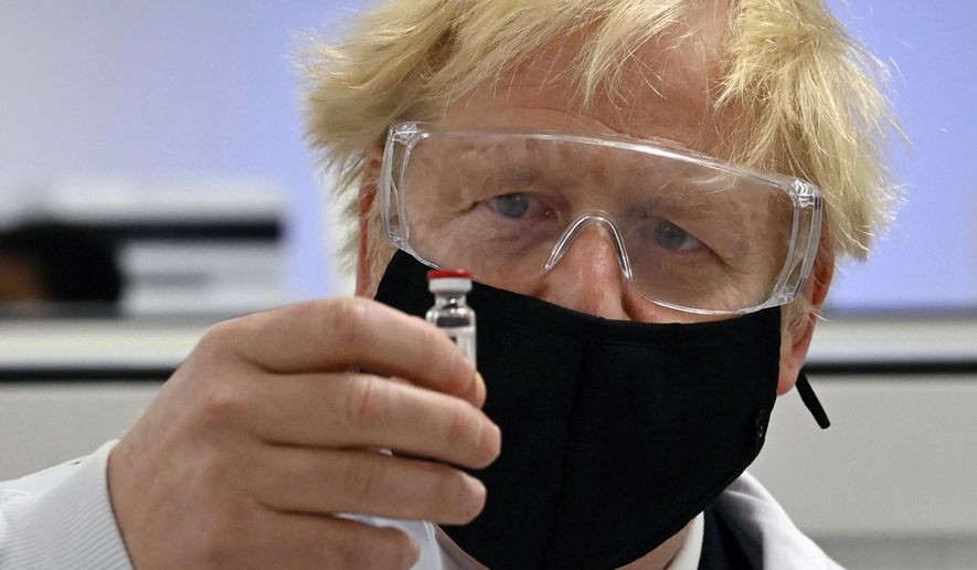 Britain&#39;s Prime Minister Boris Johnson holds a vial of the Oxford/AstraZeneca vaccine Covid-19 candidate vaccine, known as AZD1222, at Wockhardt&#39;s pharmaceutical manufacturing facility in Wrexham, Wales, Monday, Nov. 30, 2020. (Paul Ellis/PA via AP)