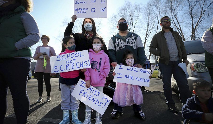 Barbara Roque, top left, holds up a sign during a Voice for Choice - Open Our Schools rally in Horsham, Pa., Sunday, Nov. 29, 2020. Joining her are her children, from left to right, Elaina, Emily, Erica and her husband, David. The group holding the event said their rally is about having the choice to choose from in-person Instruction or virtual. (David Maialetti/The Philadelphia Inquirer via AP)