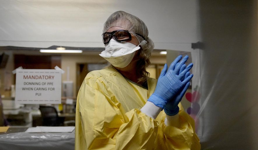 Registered nurse Shelly Girardin prepares to go on rounds after donning personal protective equipment inside an area of Scotland County Hospital sealed off with plastic to care for the influx of COVID-19 patients Tuesday, Nov. 24, 2020, in Memphis, Mo. The coronavirus pandemic is devastating rural hospitals, including the tiny 25-bed facility. (AP Photo/Jeff Roberson) ** FILE **