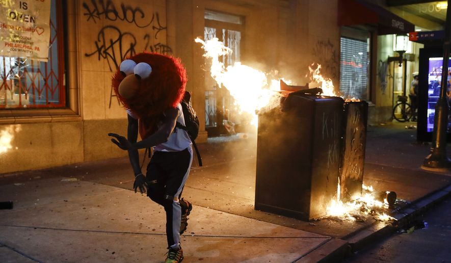 A protester in an Elmo mask dances as a street fire burns on May 30, 2020, during a protest in Philadelphia over the death of George Floyd, a Black man who was killed while in police custody in Minneapolis on May 25. (AP Photo/Matt Rourke)  ** FILE **