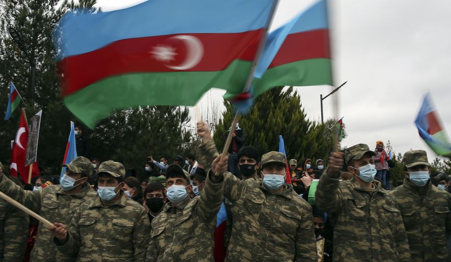 Azerbaijani soldiers wave national flags as they celebrate the transfer of the Lachin region to Azerbaijan&#39;s control, as part of a peace deal that required Armenian forces to cede the Azerbaijani territories they held outside Nagorno-Karabakh, in Aghjabadi, Azerbaijan, Tuesday, Dec. 1, 2020. Azerbaijan has completed the return of territory ceded by Armenia under a Russia-brokered peace deal that ended six weeks of fierce fighting over Nagorno-Karabakh. Azerbaijani President Ilham Aliyev hailed the restoration of control over the Lachin region and other territories as a historic achievement. (AP Photo/Emrah Gurel